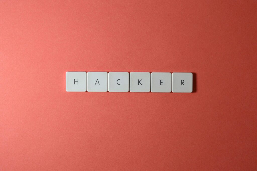 Close-up of the word 'HACKER' made with letter tiles on a red background, emphasizing cybersecurity.