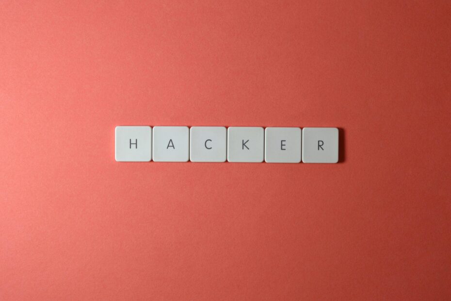 Close-up of the word 'HACKER' made with letter tiles on a red background, emphasizing cybersecurity.